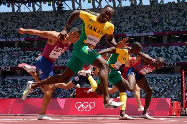 Jamaica's Hansle Parchment, foreground, crosses the finish line ahead of Chesapeake's Grant Holloway, right, to win the 110-meter hurdles final on Wednesday night at the Tokyo Games.