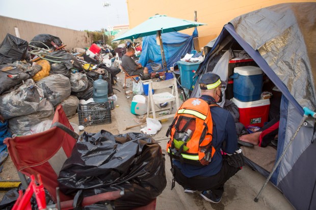 Michael Wright of Wound Walk OC offers his services to a homeless man living adjacent to the 22 Freeway in Garden Grove in 2021. (Photo by Drew A. Kelley, Contributing Photographer)