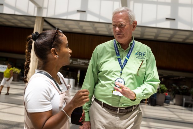 Don Bradway helps Menorca Collazo with questions about the airport after her flight had been delayed several hours at Norfolk International Airport in Norfolk, Virginia, on July 19, 2024. (Billy Schuerman / The Virginian-Pilot)