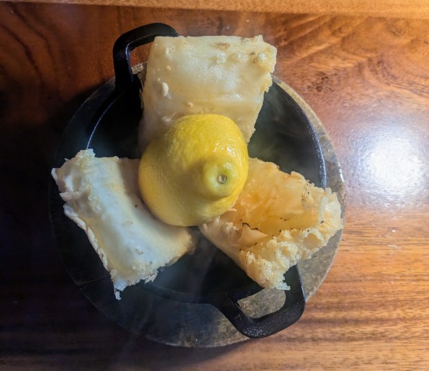 The saganaki was brought out in a mini black cast iron serving bowl, lit on fire, then put out by a squeeze of lemon juice. (Avery Goodstine/freelance)