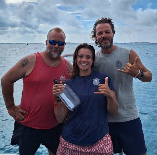 Chris Gauntlett (left), Phoebe Eggar (center) and Justin Hendrix (left) display the message found in the water off the coast of Bermuda. (Photo courtesy of Blue Water Divers Bermuda)