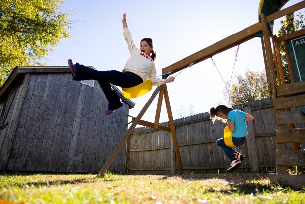 Penelope Holbert, 8, launches herself from a swing in the backyard while playing with her sister Harper Holbert, 6, at their home in Virginia Beach, Virginia, on Nov. 19, 2023. (Billy Schuerman / The Virginian-Pilot)