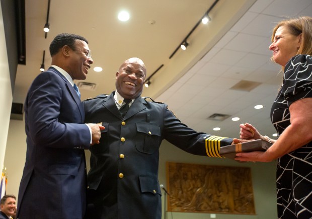 New Norfolk Fire Chief Sidney Carroll, center, gets congratulations from Norfolk Mayor Kenny Alexander as Carroll's wife Sally Carroll holds the Bible after the oath of office was administered by the Hon. Tasha D. Scott, Chief Judge of Circuit Court. The Swearing-In ceremony was held Friday morning, June 28,2024 in the MacArthur Memorial Theater in downtown Norfolk,VA. Bill Tiernan/ For The Virginian-Pilot