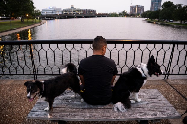 Sam Huerto sits with his dogs Pudge and Wanda on the Botetourt Foot Bridge on the Hague water front in Norfolk, Virginia, on Aug. 2, 2023. (Billy Schuerman / The Virginian-Pilot)