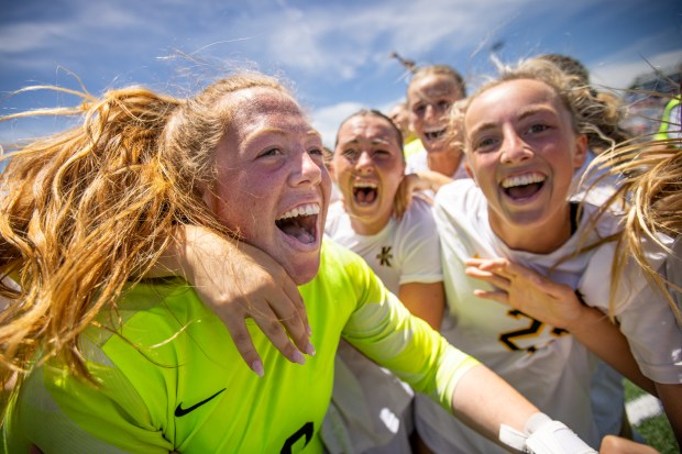 Kellam players swarm goalkeeper Anna Wise (00) after Kellam defeated First Colonial 4-2 in penalty kicks in the class 5 soccer state championships at J.R. Tucker High School in Henrico, Virginia, on June 8, 2024. (Billy Schuerman / The Virginian-Pilot)